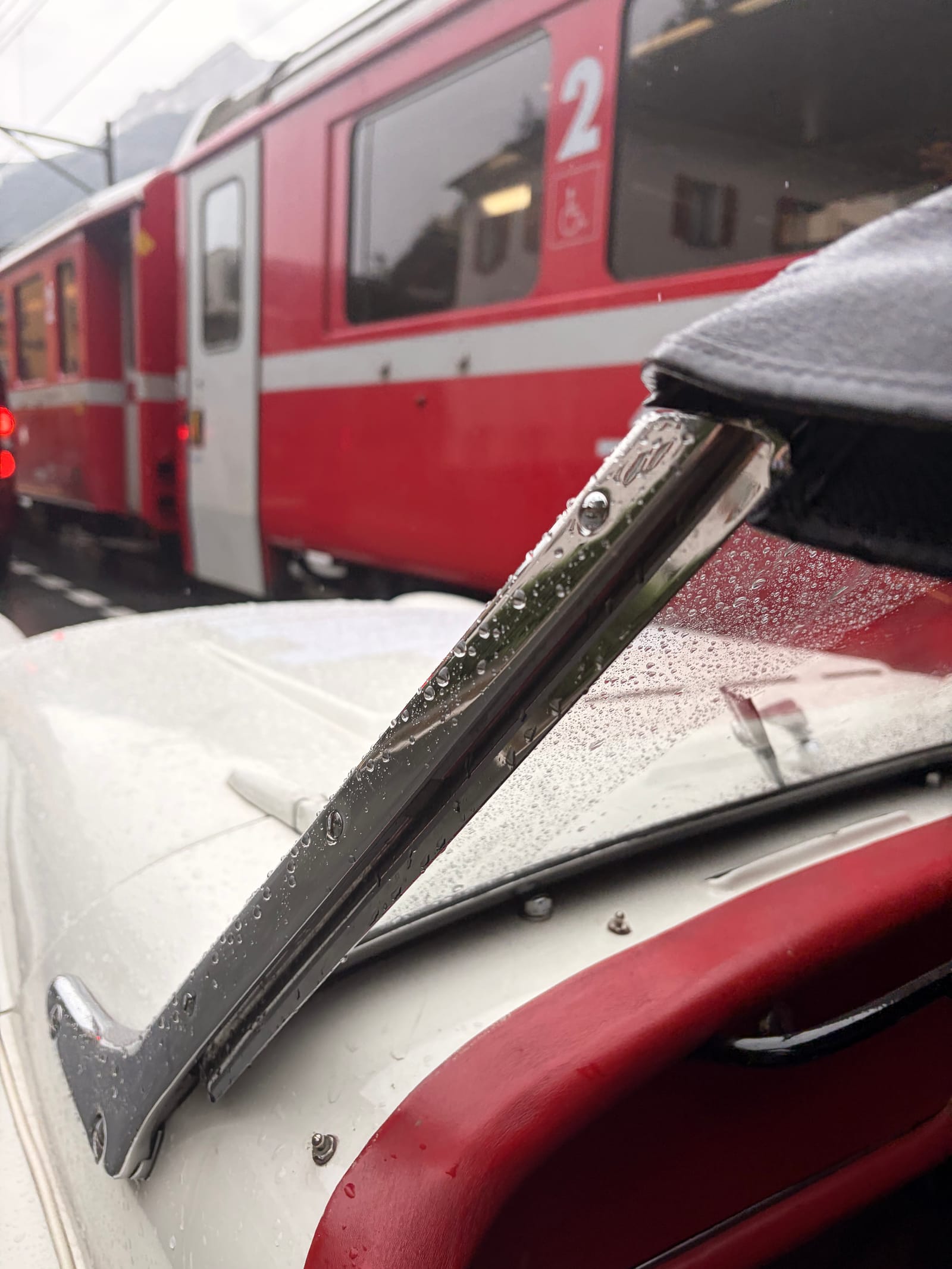 A red Rhaetian Railway carriage right alongside TS2's wet hood and door, close enough to touch