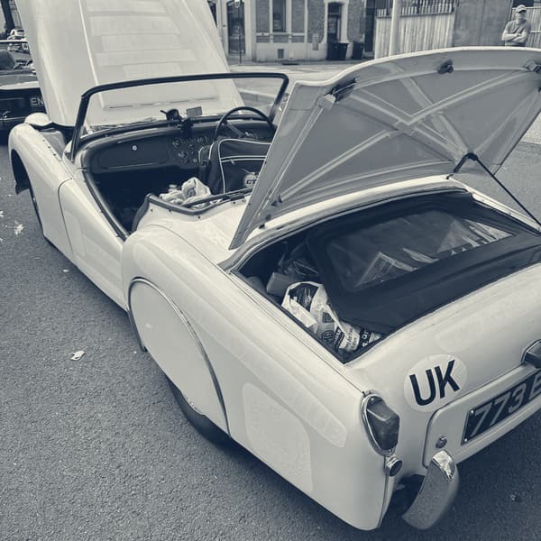 TS2 at the kerb in Amiens with both her bonnet and boot lid standing open, luggage visible in the boot, town houses behind
