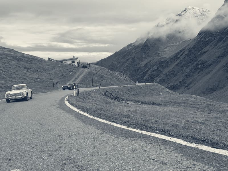 A hairpin on the Umbrail climb, a Triumph ahead on the bend and snow on the peaks above