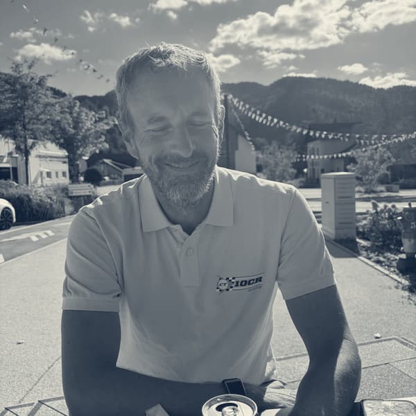 Andy at a table outside the patisserie with a steel travel cup, in his 10CR polo, the road book and a map underneath