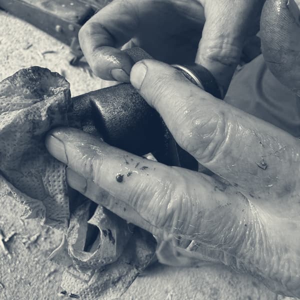 Oily hands wiping the old clutch slave cylinder on a blue paper towel, dark specks visible in the fluid