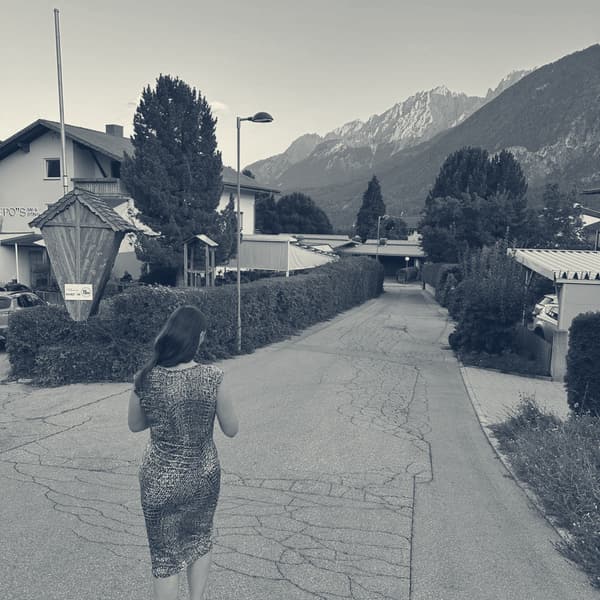 Evie walking up the lane towards the hotel, last light catching the jagged peaks at the head of the valley