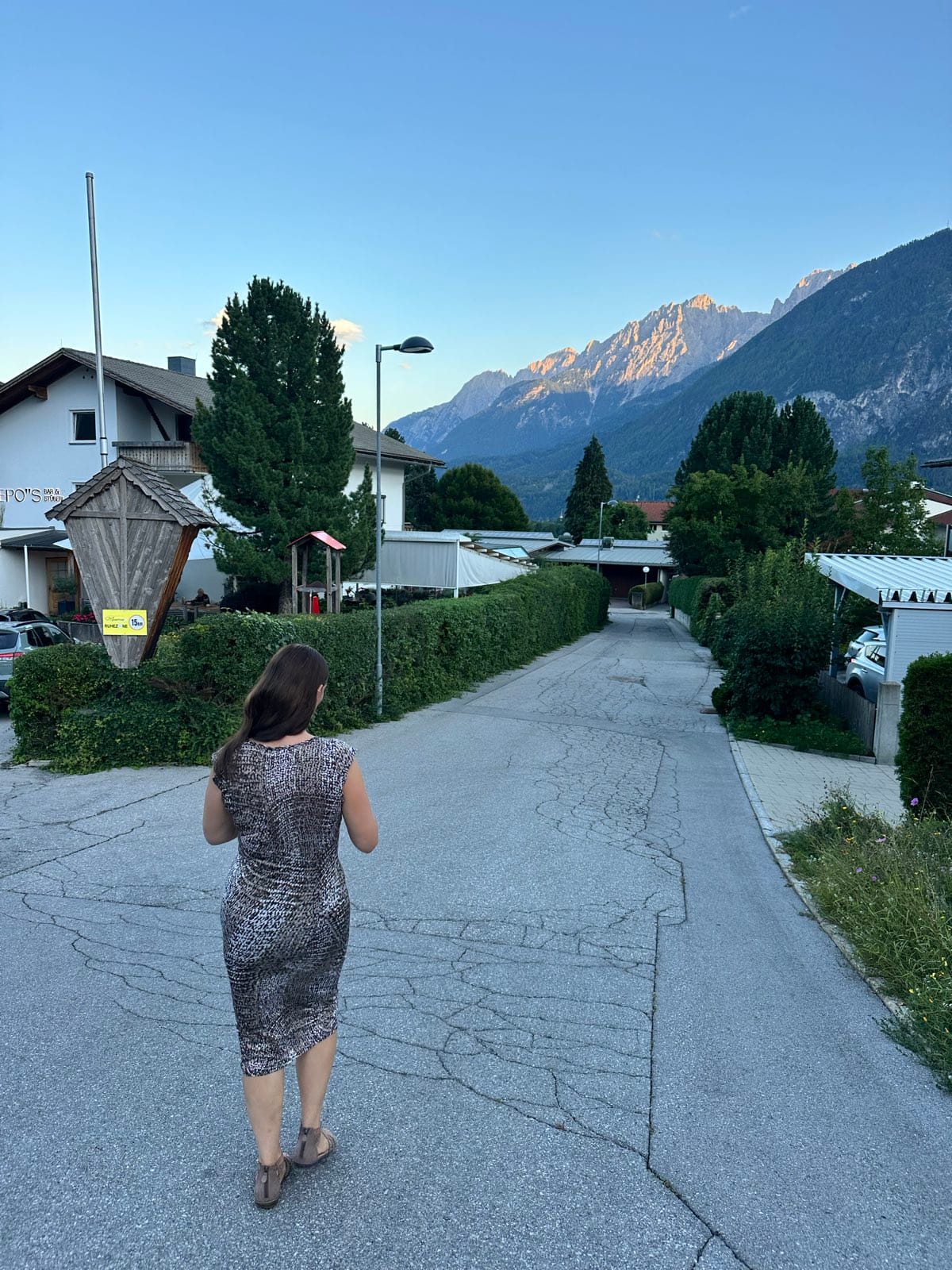 Evie walking up the lane towards the hotel, last light catching the jagged peaks at the head of the valley