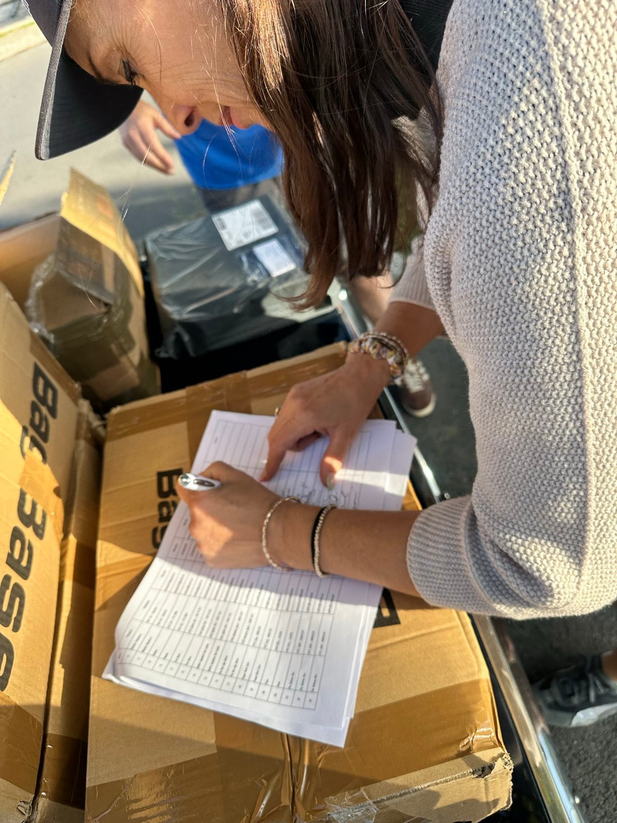 Evie leaning over the same start list, signing her name against the box lid