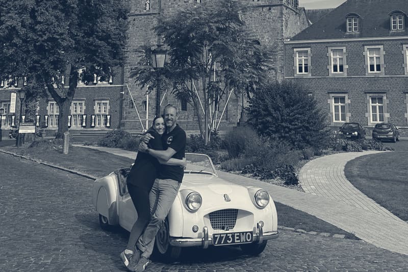 Evie and Andy hugging beside TS2 at the front of Rolduc Abbey, the finish