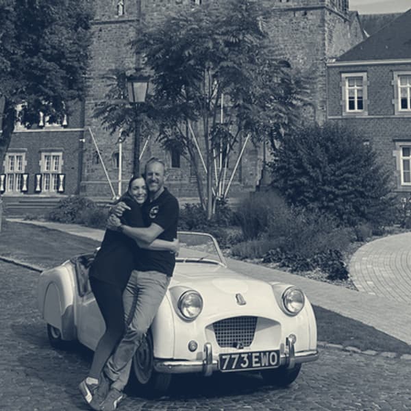 Evie and Andy hugging beside TS2 at the front of Rolduc Abbey, the finish
