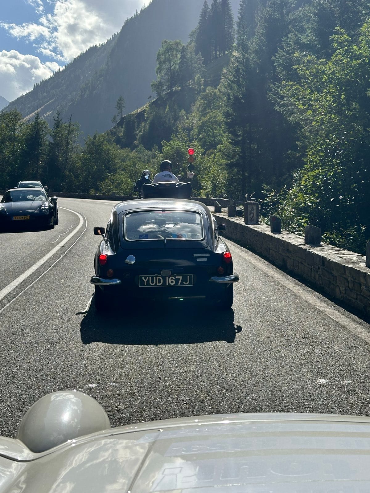 The view over TS2's bonnet following a black Triumph GT6 along a walled mountain road