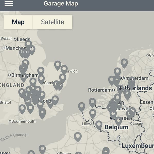 A phone screen headed Garage Map, red pins clustered thickly over England, Belgium and Paris, and a lone blue pin marking us in an empty stretch of northern France
