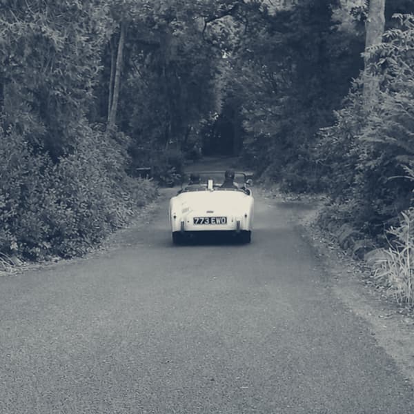 TS2 setting off from home, two up with the hood down, heading away down the lane