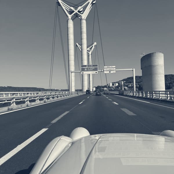 The view over TS2's bonnet on the approach to a tall cable stayed bridge, its white pylons against a clear sky
