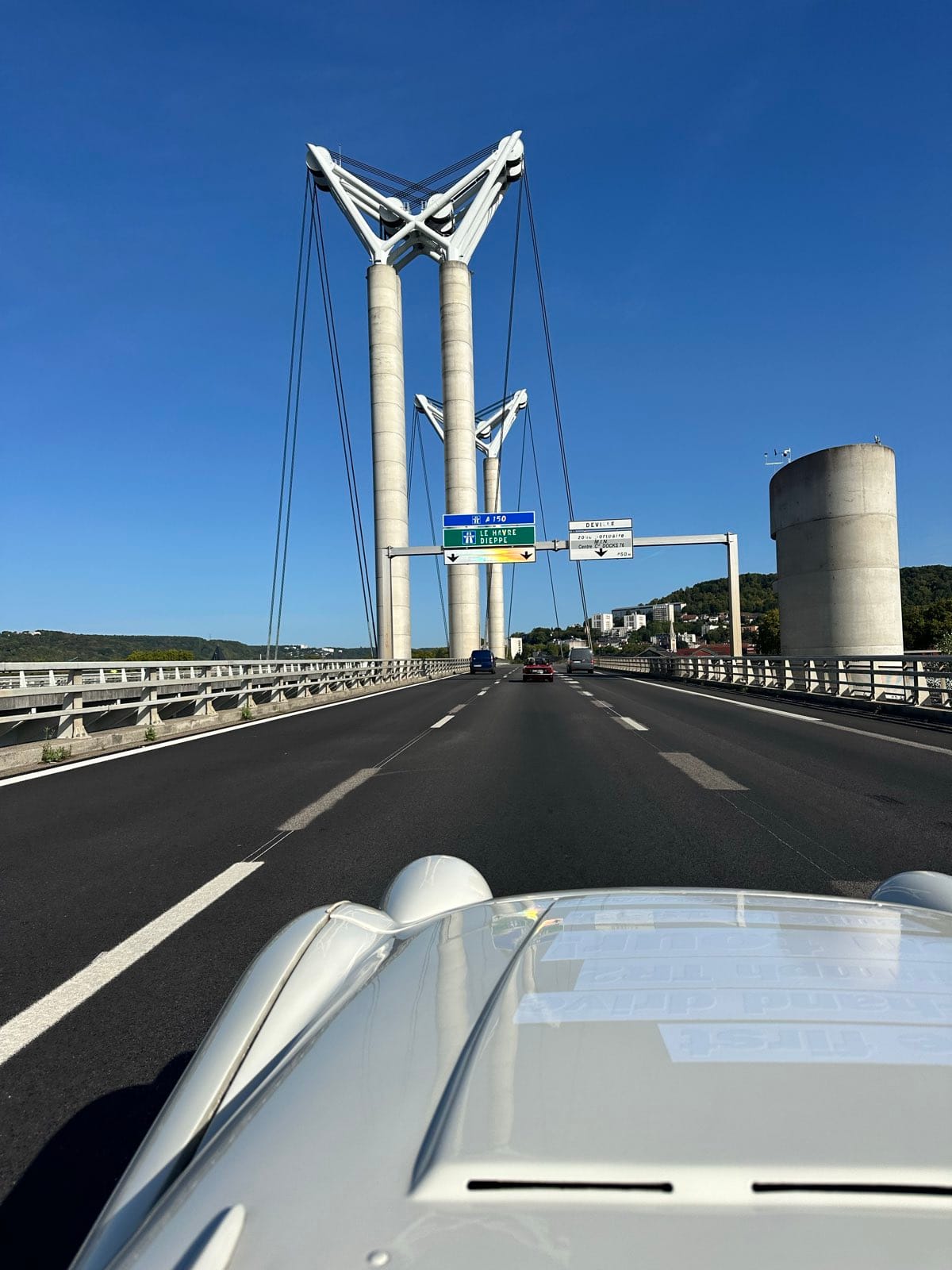 The view over TS2's bonnet on the approach to a tall cable stayed bridge, its white pylons against a clear sky