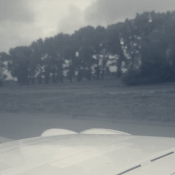 TS2's white bonnet in the rain on the Belgian motorway, a blue services sign ahead reading Jabbeke 500 m
