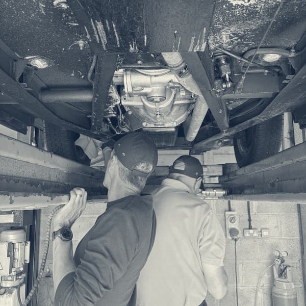 The two of us working under the car on the lift, both in caps