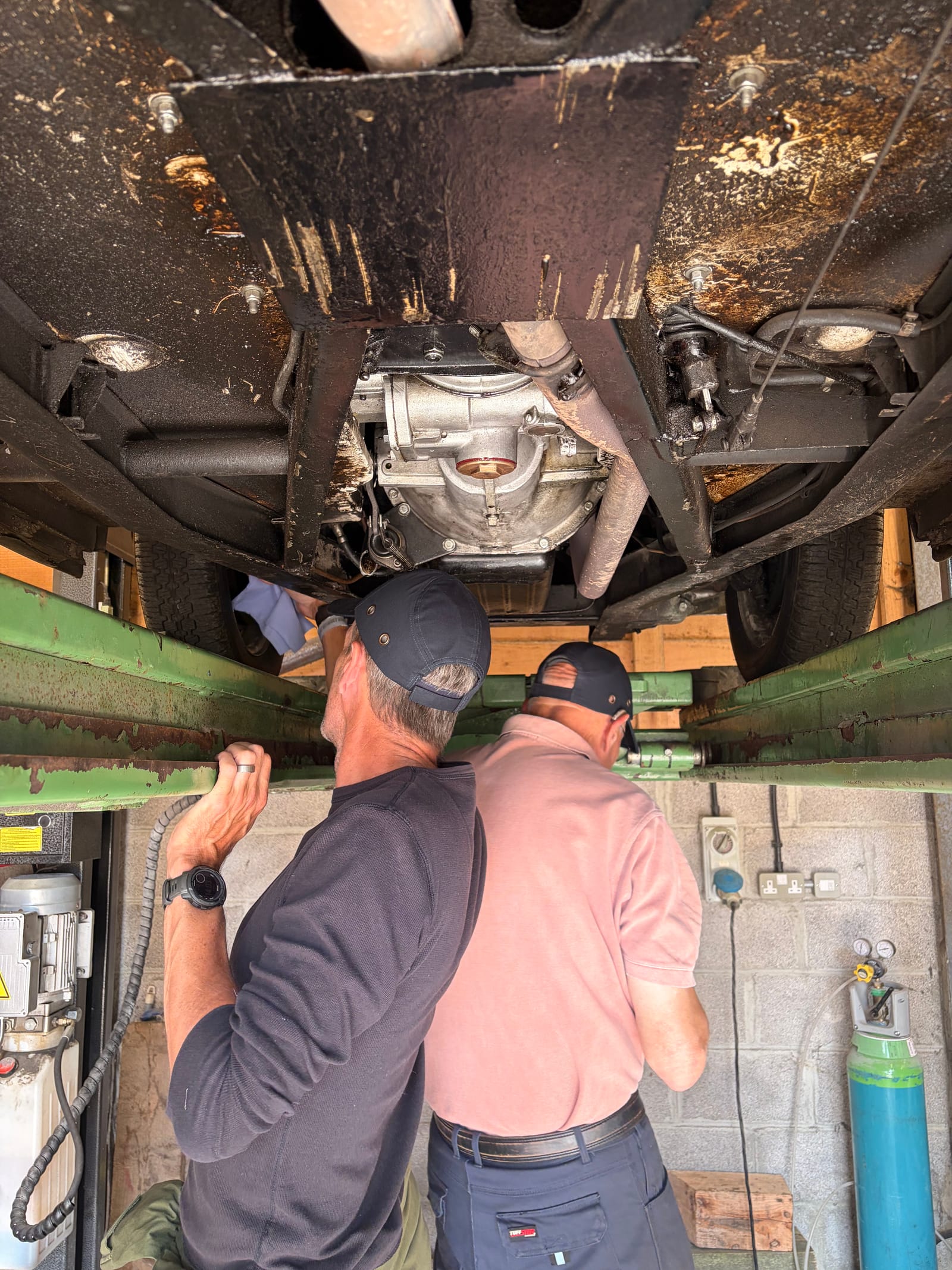 The two of us working under the car on the lift, both in caps