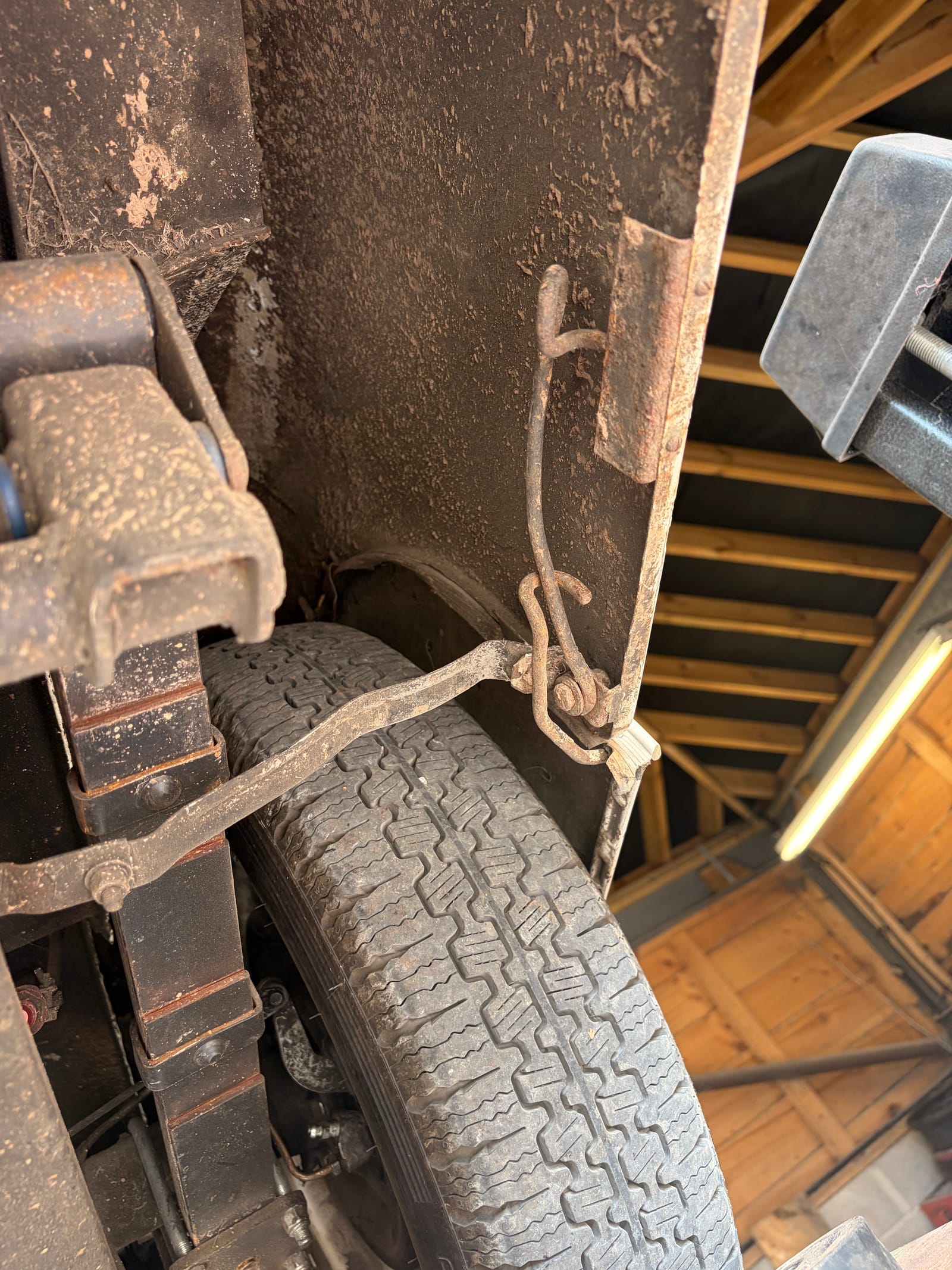 The brake backplate and its linkage exposed, the wheel leaning against the car beside it