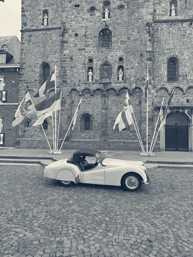 TS2 side on, hood up, on the cobbles in front of Rolduc abbey with a row of flags on poles behind her