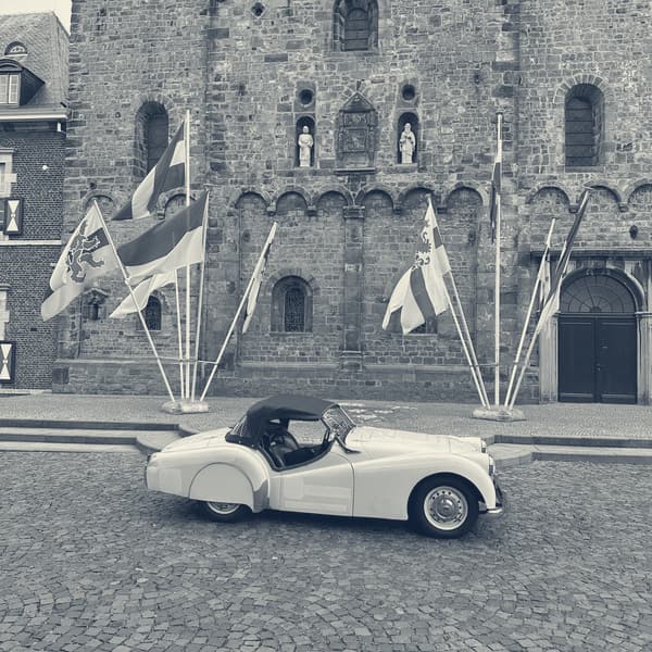 TS2 side on, hood up, on the cobbles in front of Rolduc abbey with a row of flags on poles behind her