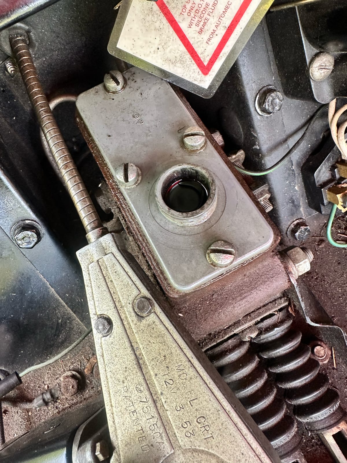 The master cylinder with its cap off and dark fluid visible, an Automec label alongside reading top up only with DOT 5 silicone brake fluid