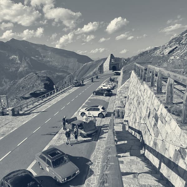 Looking down from the wall onto the pass road below, cars working their way up towards a tunnel portal