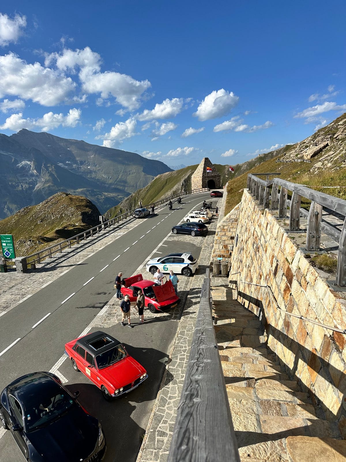 Looking down from the wall onto the pass road below, cars working their way up towards a tunnel portal