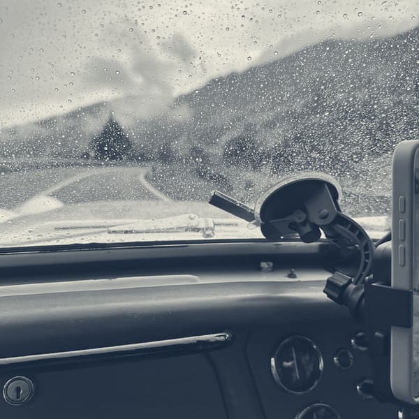 Rain running across the windscreen with a misty mountain barely visible ahead