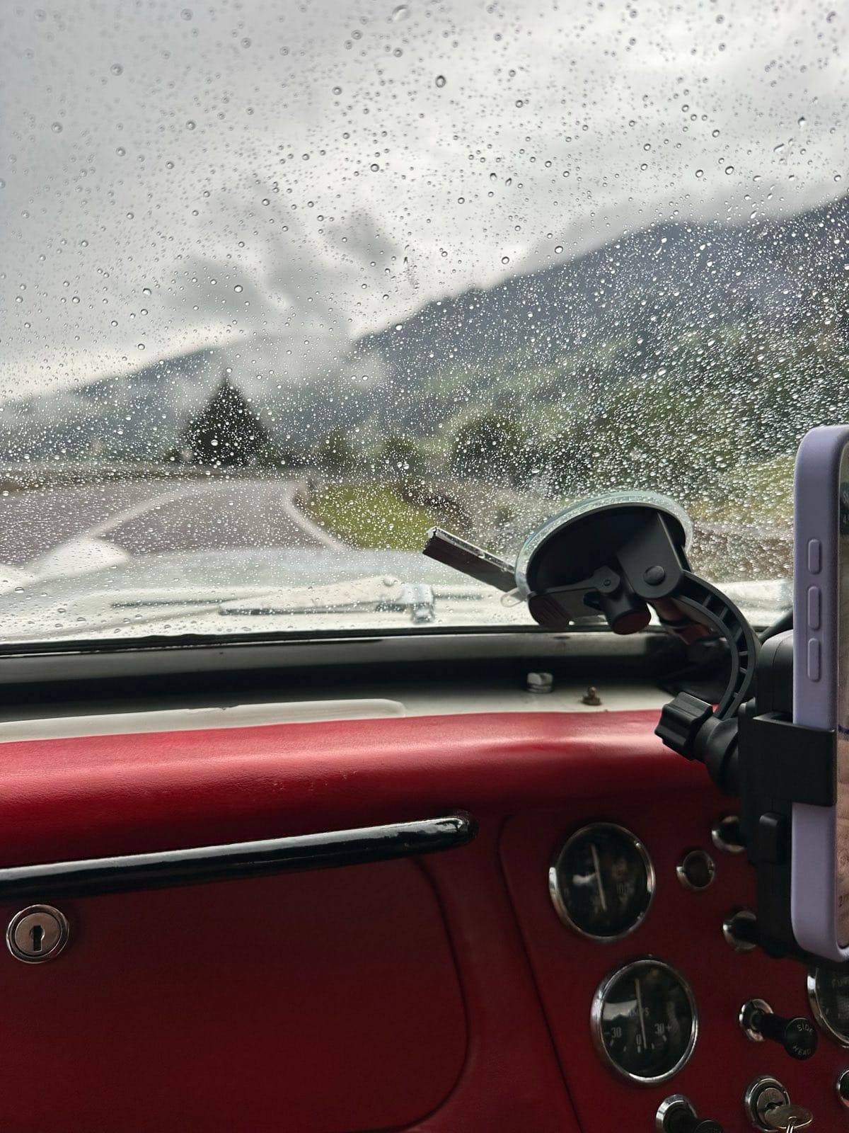 Rain running across the windscreen with a misty mountain barely visible ahead