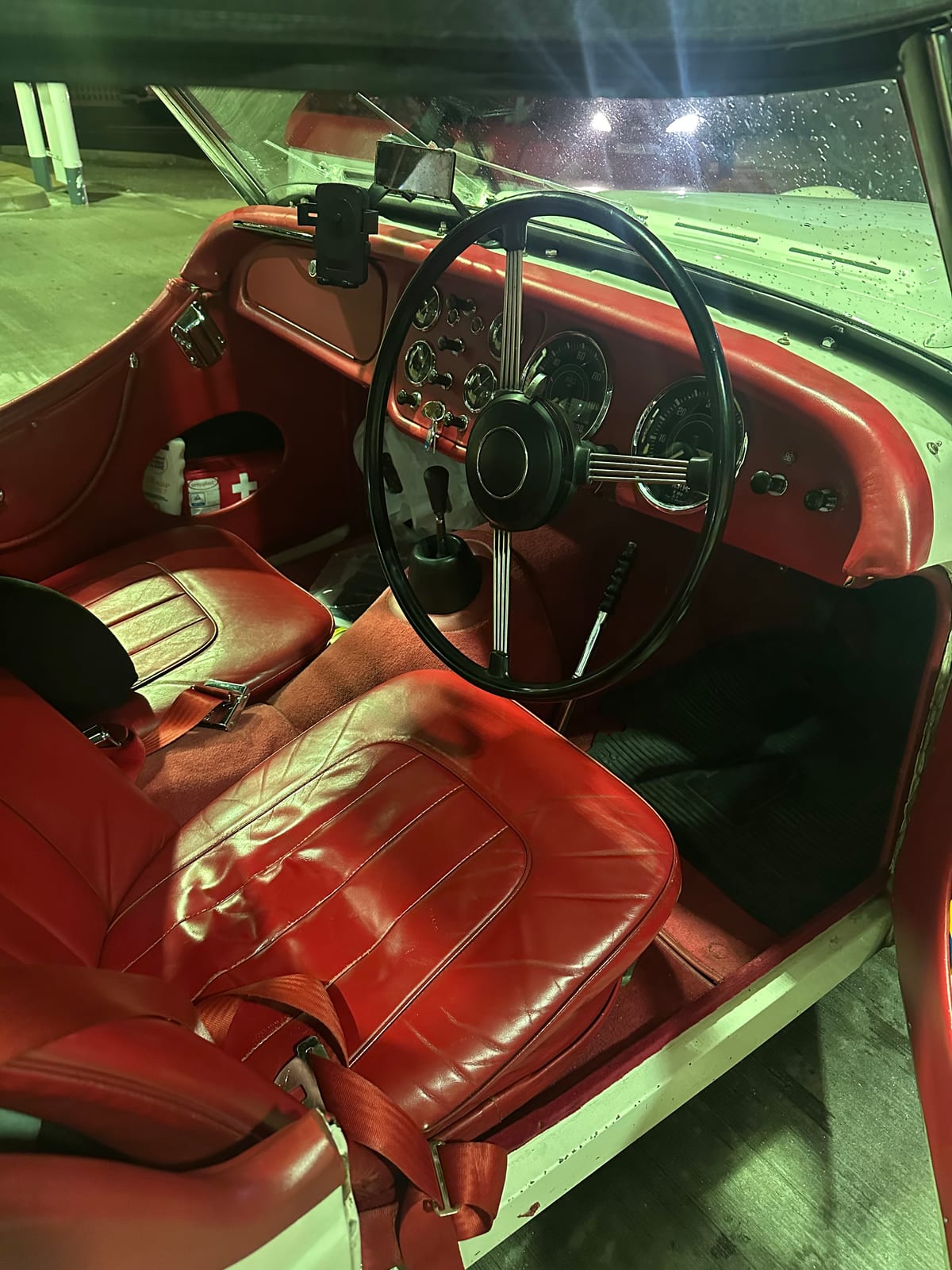 TS2's red leather interior lit by the forecourt lights, big black steering wheel, the dials dark and the seats empty