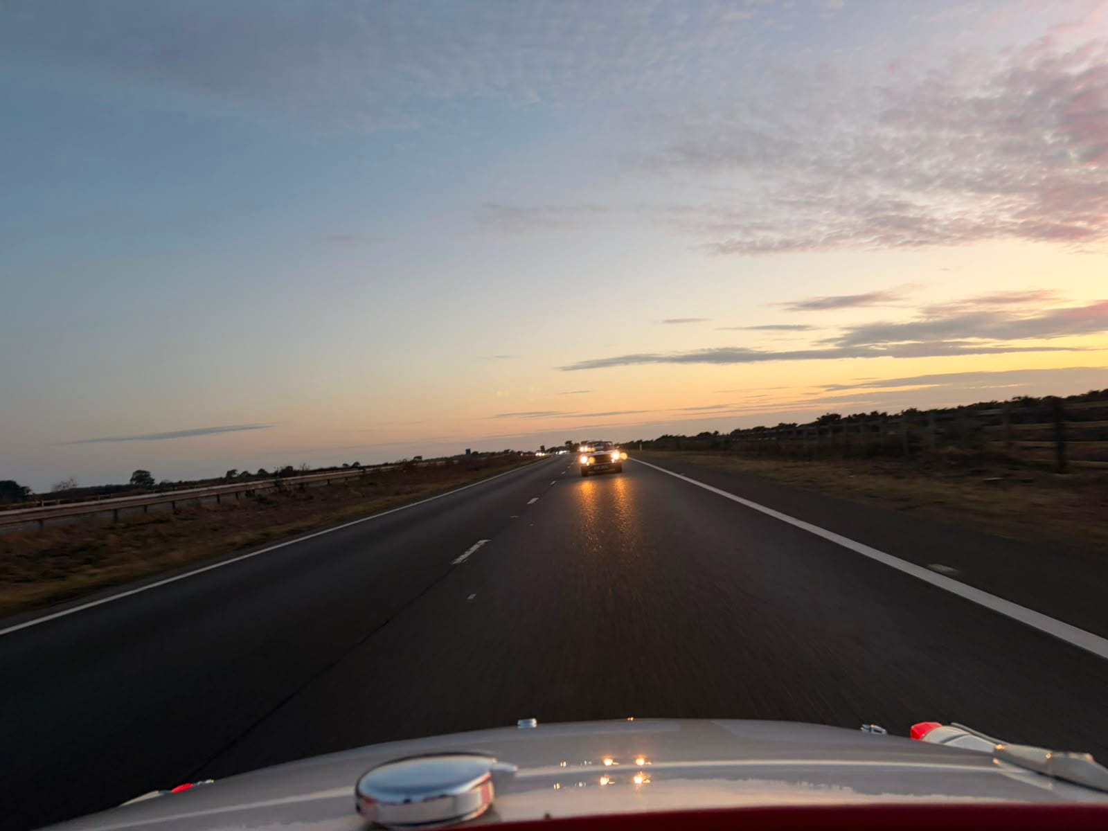 The view back over TS2's rear deck at dusk, a car following with headlights on, the sky orange over the heath