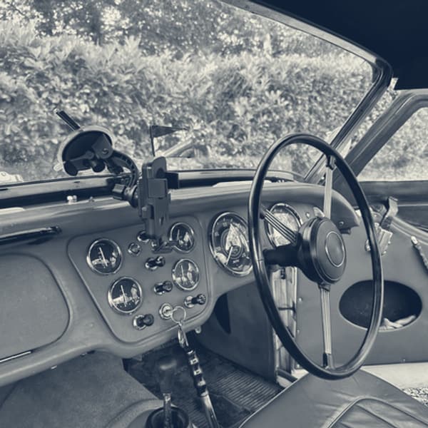 Inside TS2 with the roof on, red dashboard and steering wheel, a small round mirror on the windscreen frame and the black roof wrapping down at the sides
