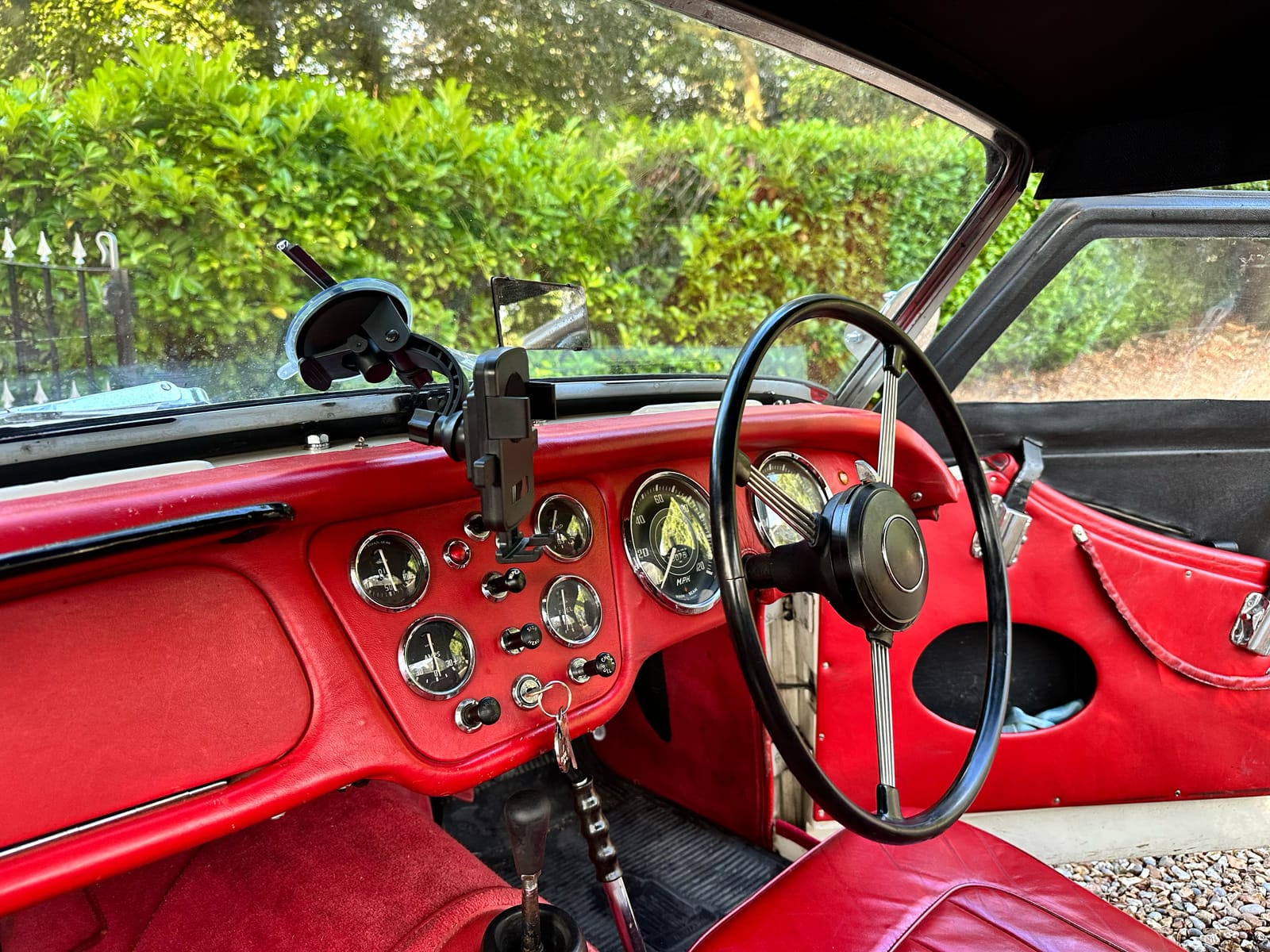 Inside TS2 with the roof on, red dashboard and steering wheel, a small round mirror on the windscreen frame and the black roof wrapping down at the sides