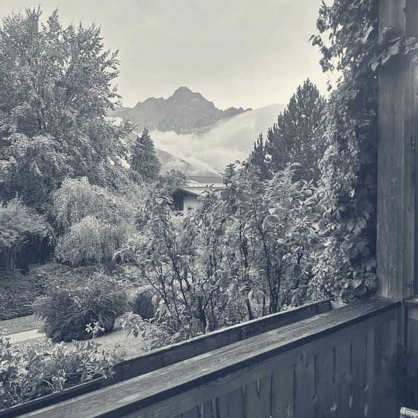 The view from the hotel balcony, wet garden below and cloud lying along a rocky ridge