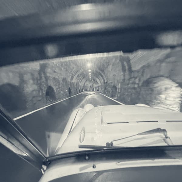 Looking through TS2's windscreen into a rough rock tunnel, a single lamp ahead and the walls close on both sides