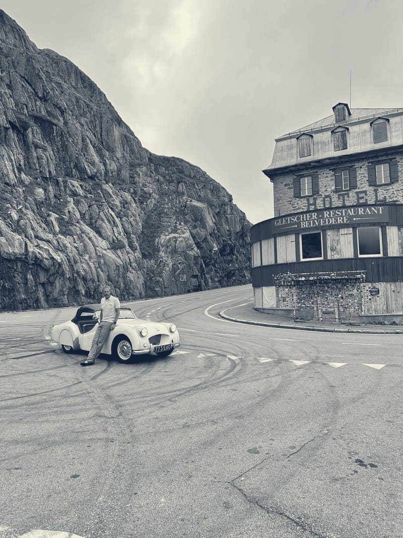 TS2 alone in the empty car park below the Hotel Belvédère on the Furka, Andy sitting on her wing, tyre marks on the tarmac