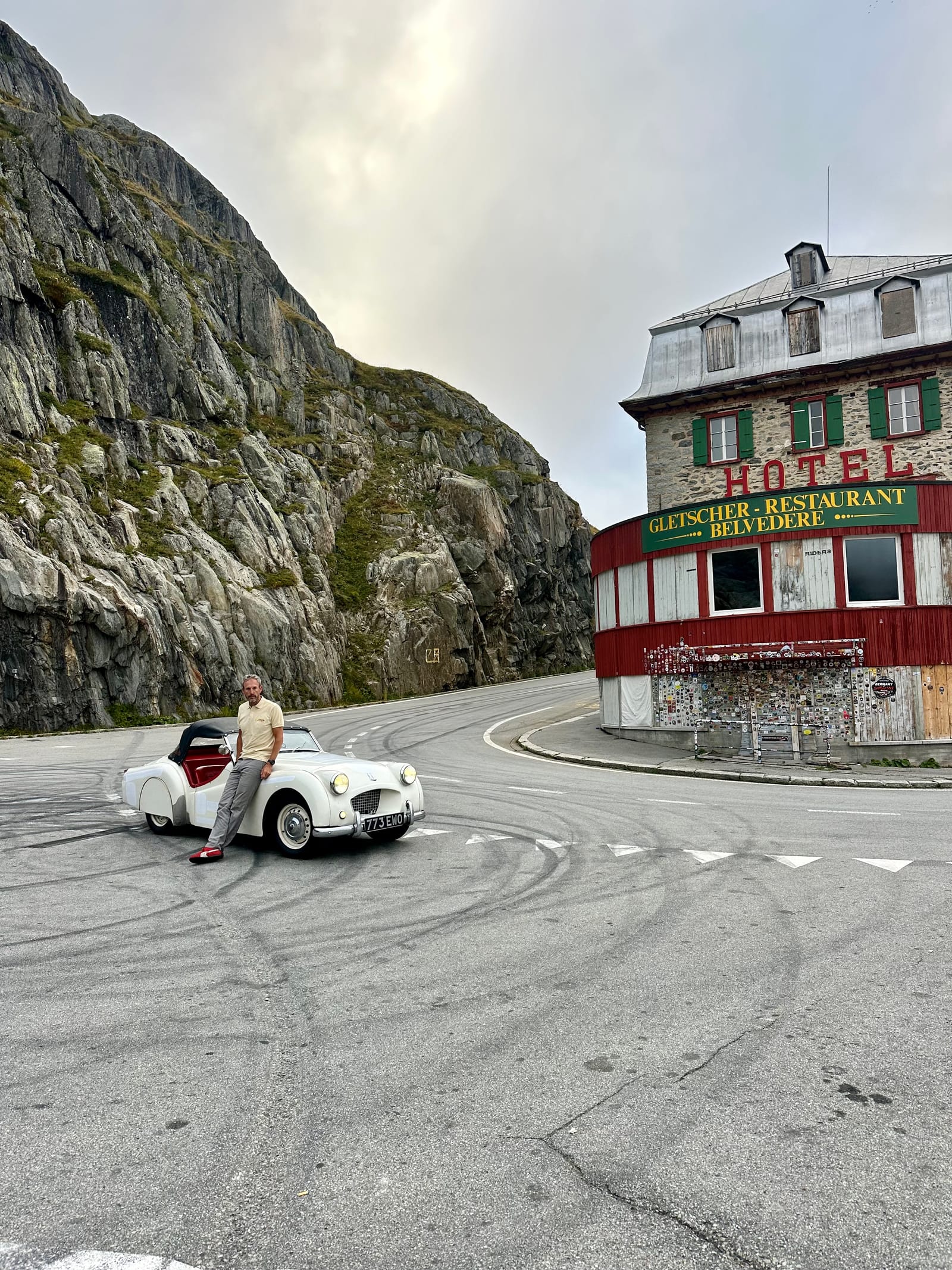 TS2 alone in the empty car park below the Hotel Belvédère on the Furka, Andy sitting on her wing, tyre marks on the tarmac