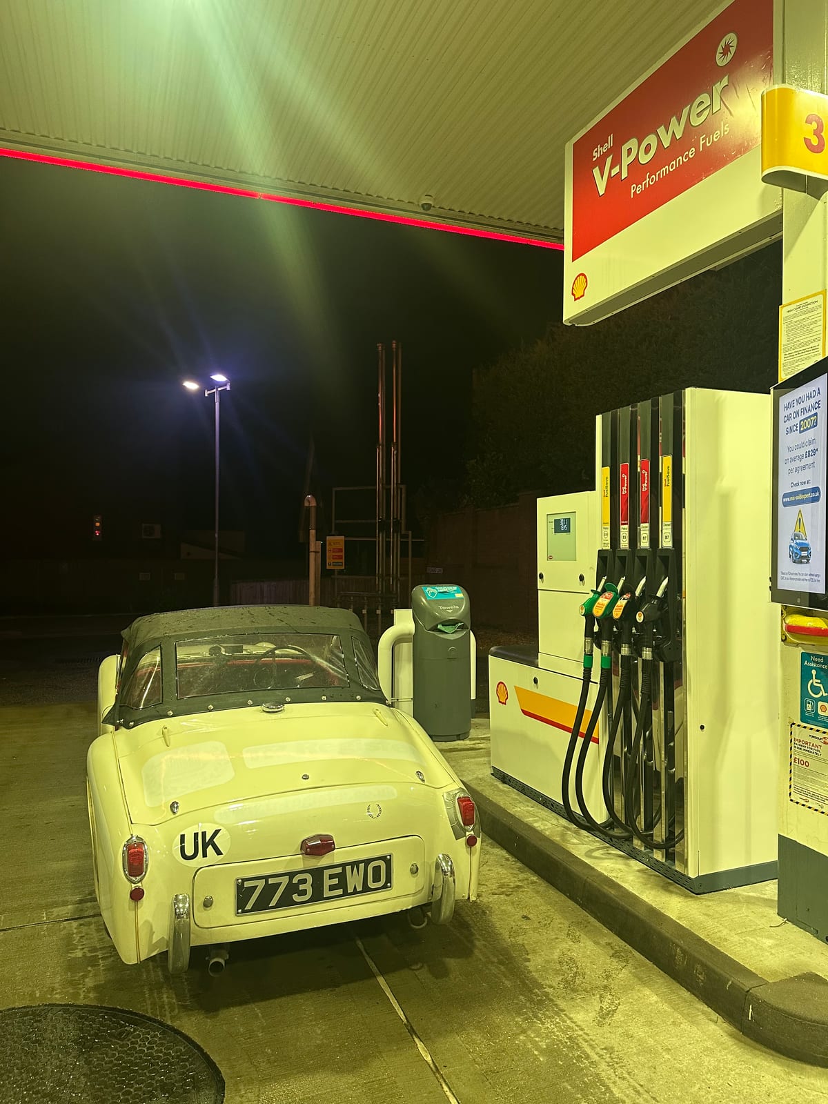 TS2 from behind on a floodlit forecourt at night, UK plate and 773 EWO under the Shell V-Power canopy, everything else black